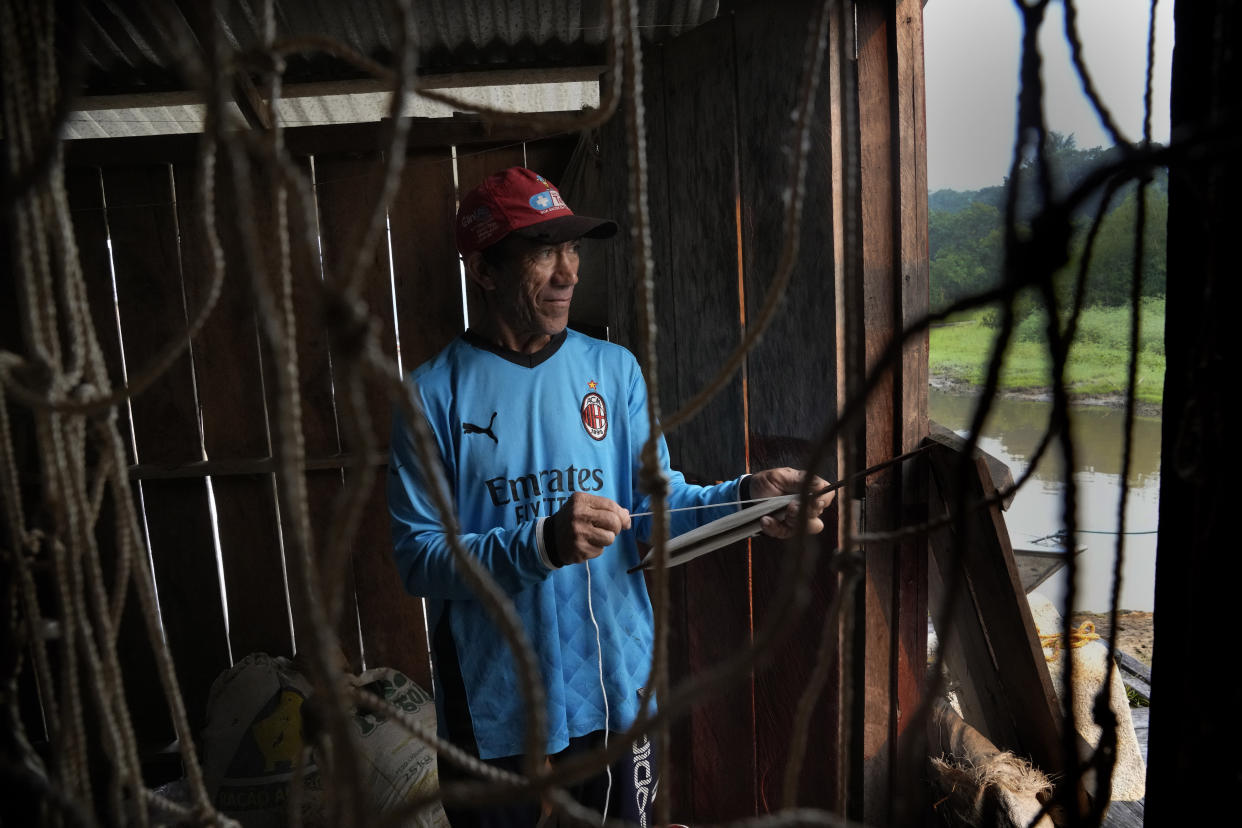 Ovidio Osmali Visco De Lima, winds thread to weave nets at a floating warehouse in San Raimundo settlement, at Medio Jurua region, Amazonia State, Brazil, Monday, Sept. 5, 2022. To catch pirarucu, fishermen use special, stronger nets they weave themselves. The holes are large enough to allow smaller specimens to go through, as taking fish under five feet is prohibited. (AP Photo/Jorge Saenz)