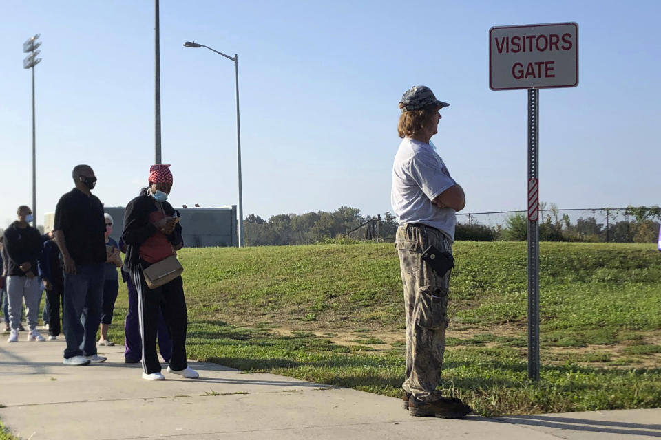 In this Thursday, Oct. 15, 2020, photo voters line up at Mallard Creek High School during the first day of in-person voting ahead of the Nov. 3 elections in Charlotte, N.C. (AP Photo/Laurie Kellman)