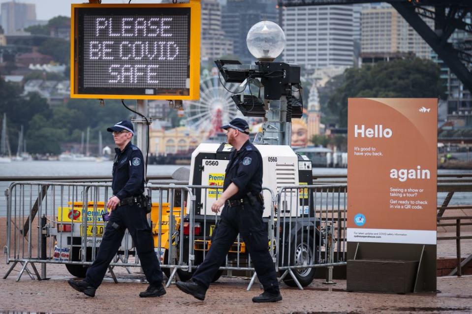 New South Wales police officers walk past signs on display in front of the Sydney Opera House.