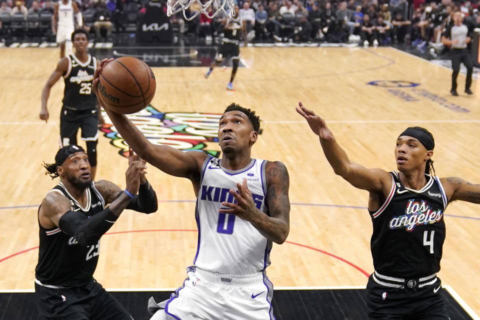 Sacramento Kings guard Malik Monk (0) shoots as Los Angeles Clippers forward Robert Covington (23) and guard Brandon Boston Jr. (4) defend during the first half of an NBA basketball game Saturday, Dec. 3, 2022, in Los Angeles. (AP Photo/Mark J. Terrill)