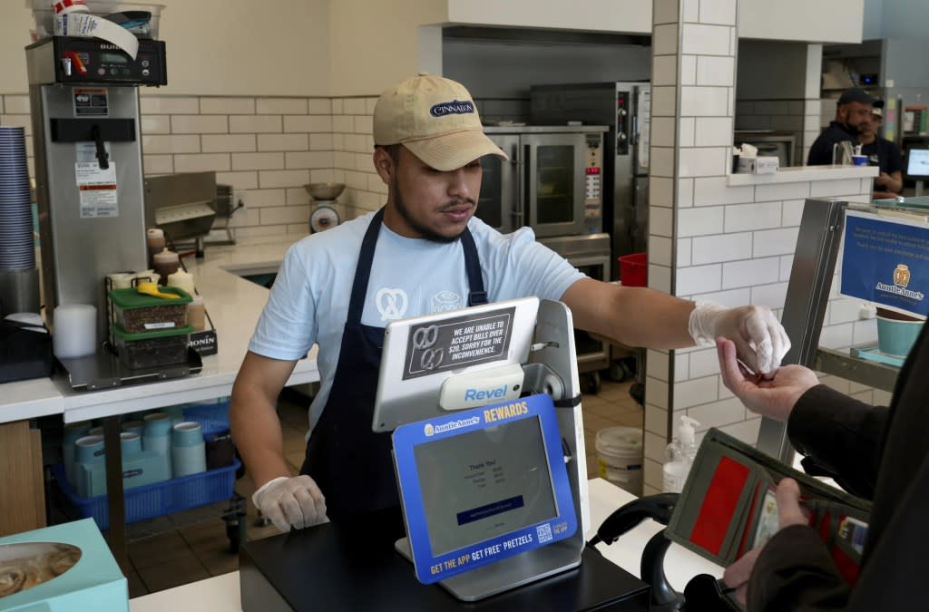 An employee collects payment at an Auntie Anne’s and Cinnabon store in Livermore, Calif., Thursday, March 28, 2024. (AP Photo/Terry Chea)