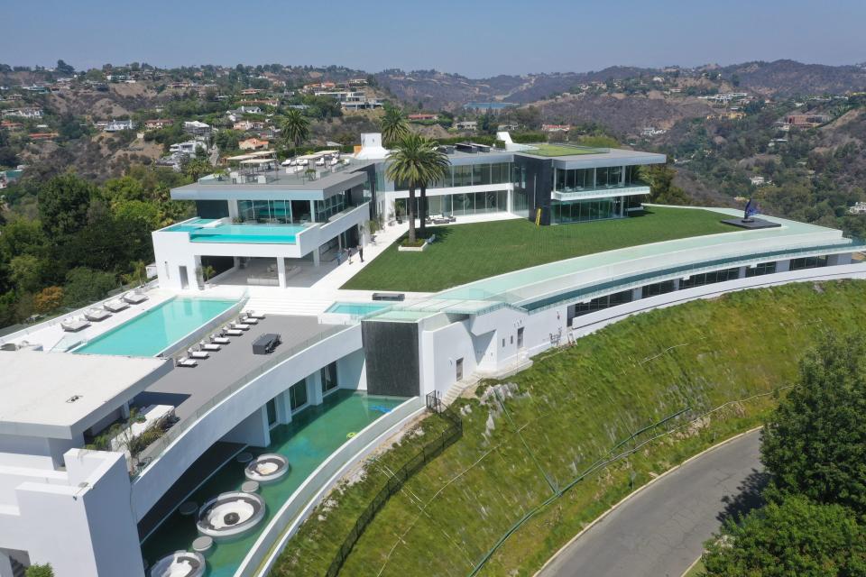 an aerial view of a white mansion, The One Bel Air, and its pools