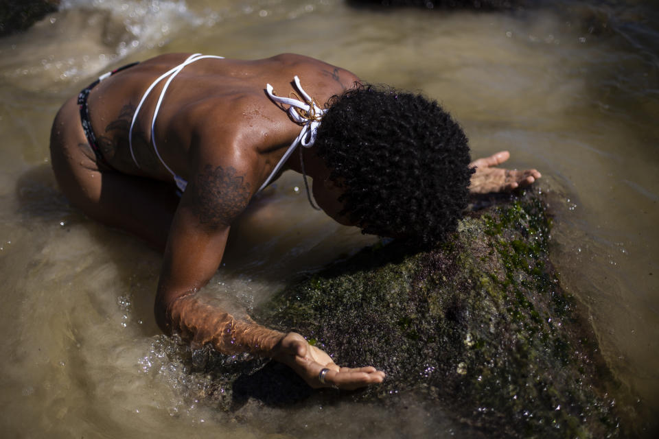 Shirley Azedi, who said she's lost work as a housekeeper due to the COVID-19 pandemic, prays during a ceremony in honor of the Goddess of the Sea Yemanja on Praia Vermelha beach to mark the end of the year in Rio de Janeiro, Brazil, on New Year's Eve, Thursday, Dec. 31, 2020. Beaches will be closed on the night of new year's, to help curb the spread of the new coronavirus. (AP Photo/Bruna Prado)