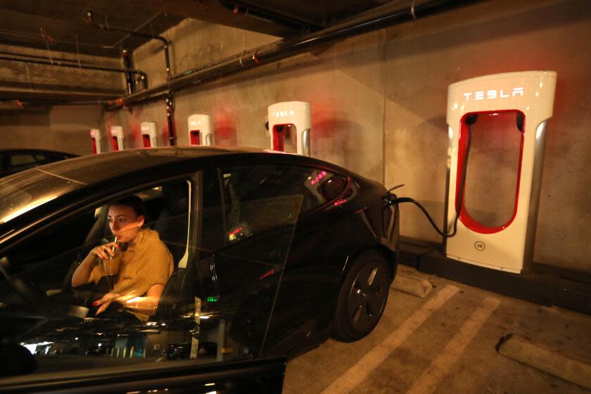 CULVER CITY, CA - SEPTEMBER 21, 2023 - Olivia Simon enjoys a drink while waiting for her Tesla to be charged at a Tesla Supercharger station inside the garage at the Haven apartment complex in Culver City on September 21, 2023. Simon was visiting the area but is not a tenant at the Haven apartments. Besides the bank of Tesla Superchargers, Tesla Gen 2 chargers are also available in the garage at the apartments. Commercial landlords are scrambling to supply charging stations to the rapidly growing number of electric vehicle owners. It's suddenly a necessity to attract and keep tenants. (Genaro Molina / Los Angeles Times)