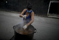 Alejandra Gómez, utilizando guantes desechables y barbijo, revuelve un guiso de lentejas afuera de un comedor popular en las afueras de Buenos Aires, Argentina, el miércoles 25 de marzo de 2020. (AP Foto / Natacha Pisarenko)