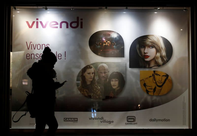 A woman walks pass by a sign of Vivendi at the main entrance of the entertainment-to-telecoms conglomerate headquarters in Paris