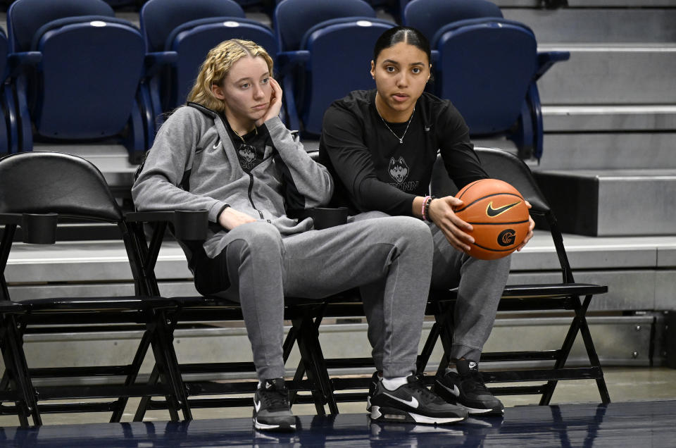 Paige Bueckers and Azzi Fudd watch the UConn Huskies warm up before a game last season. Fudd will miss the remainder of the 2023-24 season with a torn meniscus and ACL in her right knee. (Photo by G Fiume/Getty Images)