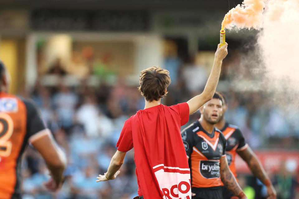 A pitch invader carrying a flare, pictured here running onto the field at PointsBet Stadium.