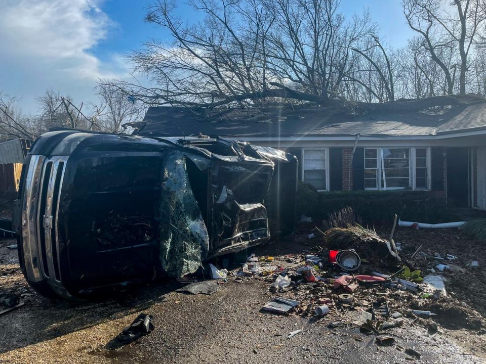 A damaged vehicle rests on its side in front of a home in Selma (AP)