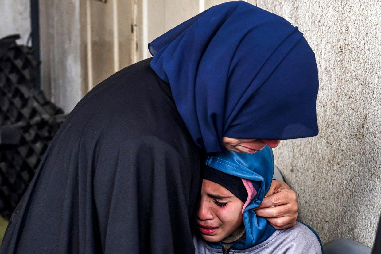 <span>A woman embraces a crying child as they mourn relatives who were killed during Israeli bombardment late the previous night in Rafah on 19 March 2024.</span><span>Photograph: Mohammed Abed/AFP via Getty Images</span>