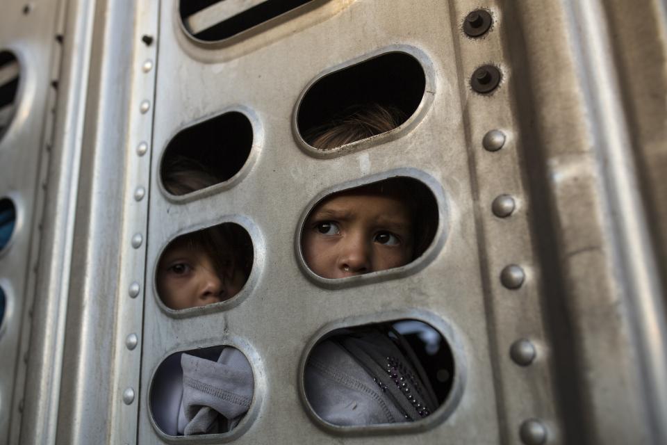 In this Nov. 12, 2018 photo, a couple of Central American migrant girls, part of the caravan hoping to reach the U.S. border, get a ride in a chicken truck, in Irapuato, Mexico. Several thousand Central American migrants marked a month on the road Monday as they hitched rides toward the western Mexico city of Guadalajara. (AP Photo/Rodrigo Abd)