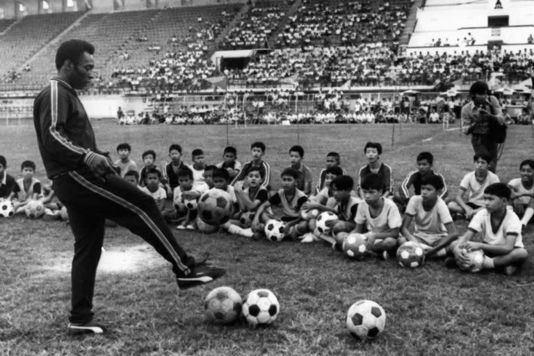 En esta foto tomada el 6 de diciembre de 1974 en Bangkok, se ve al jugador de fútbol brasileño Pelé durante una sesión de entrenamiento con juveniles de Tailandia