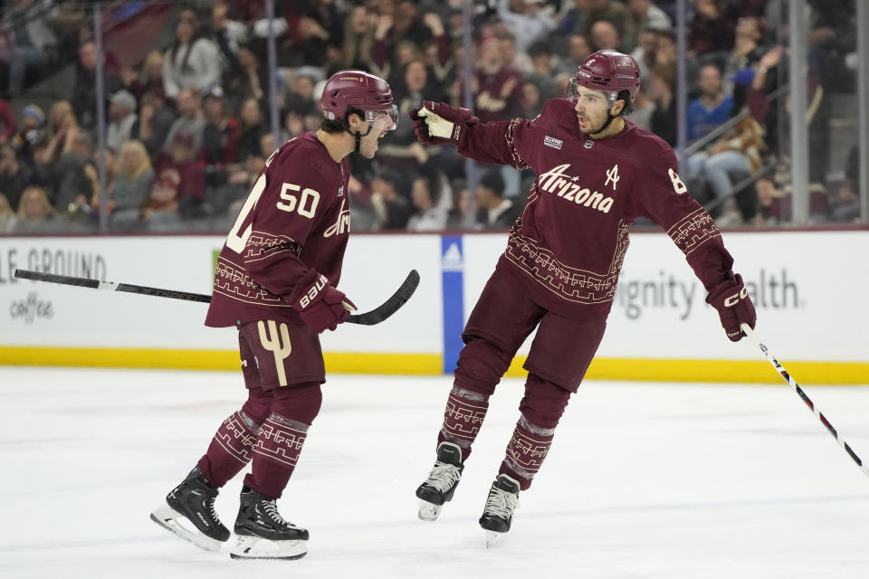 Arizona Coyotes center Nick Schmaltz (8) celebrates with defenseman Sean Durzi after scoring against the St. Louis Blues in the second period during an NHL hockey game, Wednesday, Nov. 22, 2023, in Tempe, Ariz. (AP Photo/Rick Scuteri)