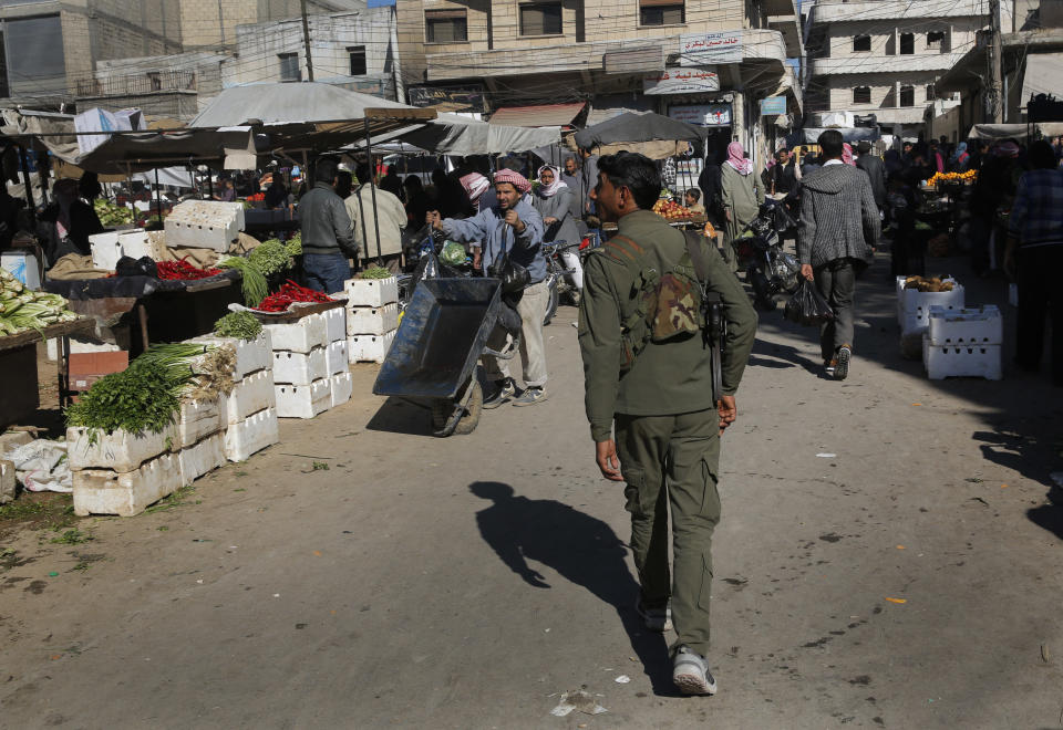 In this March 31, 2018 photo, a member of the Kurdish internal security forces, center, patrols at a popular market, in Manbij, north Syria. On Friday, Dec. 28, 2018, Syria's military said it entered the flashpoint Kurdish-held town of Manbij, where Turkey has threatened an offensive -- a claim that was refuted by U.S. troops who patrol the town. The announcement and the conflicting reports reflect the potential for chaos in the wake of the U.S. surprise decision to withdraw troops from Syria. (AP Photo/Hussein Malla)