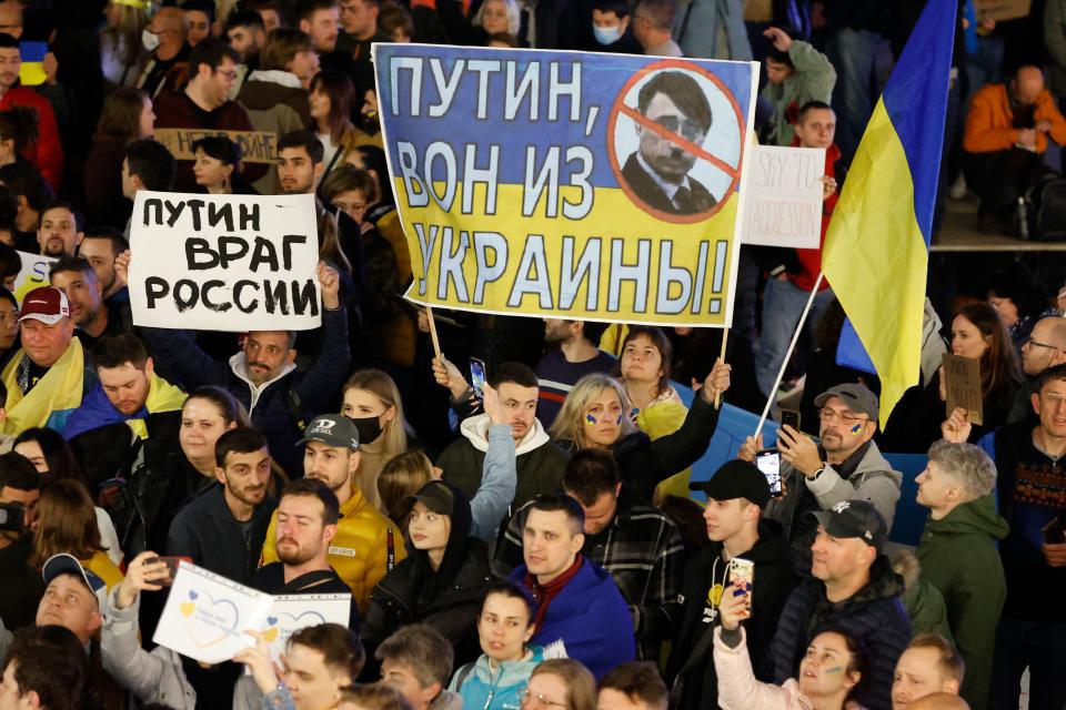 Demonstrators hold up a sign showing the Ukrainian flag with text reading in Russian 