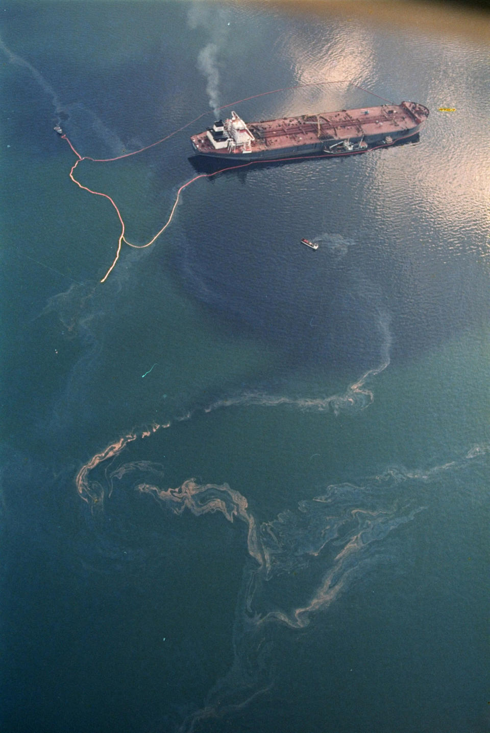 FILE - Crude oil from the tanker Exxon Valdez, top, swirls on the surface of Alaska's Prince William Sound near Naked Island on April 9, 1989. Joseph Hazelwood, the captain of the Exxon Valdez oil tanker that ran aground more than three decades ago in Alaska, causing one of the worst oil spills in U.S. history, has died, the New York Times reported. He was 75. He died in July 2022, after struggling with COVID-19 and cancer, his nephew Sam Hazelwood told the newspaper for a story reported Friday, Sept. 9, 2022. (AP Photo/John Gaps III, File)