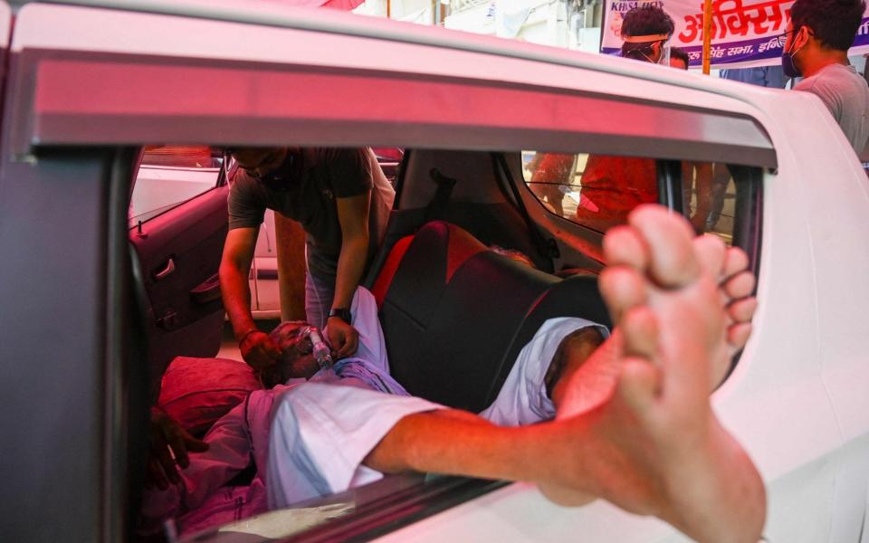 A Covid-19 coronavirus patient laying on the backsit of a car breathes with the help of oxygen provided by a Gurdwara