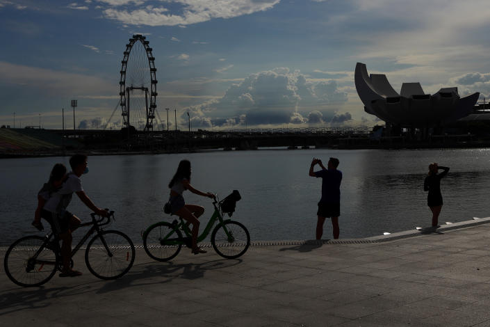 People cycle and take pictures amid the COVID-19 Omicron wave at Merlion Park on February 26, 2022 in Singapore. (Photo by Suhaimi Abdullah/NurPhoto via Getty Images)