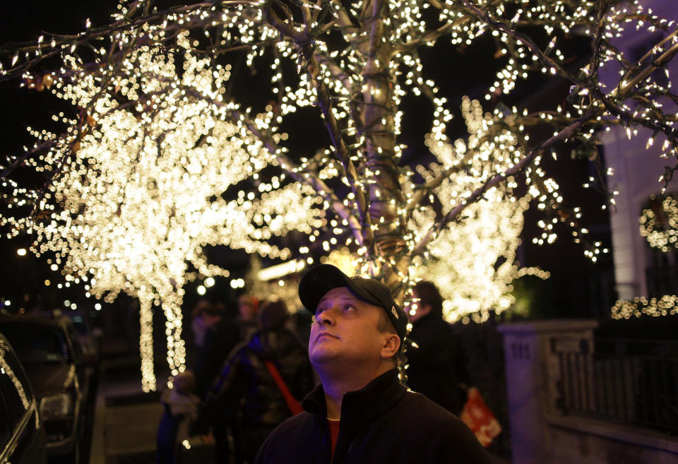 This Dec. 4, 2012 photo shows Erik Hall of Rochester, N.Y., looking up at the elaborate holiday displays during a tour in the Brooklyn borough of New York. Each holiday season, tour operator Muia takes tourists from around the world on his “Christmas Lights & Cannoli Tour” visiting the Brooklyn neighborhoods of Dyker Heights and Bay Ridge, where locals take pride in over-the-top holiday light displays. (AP Photo/Seth Wenig)