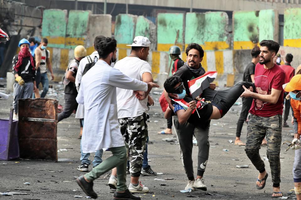 An injured protester is carried during clashes between Iraqi security forces and anti-Government protesters at Khilani Square in Baghdad, Iraq, Thursday, Nov. 14, 2019. (AP Photo/Hadi Mizban)