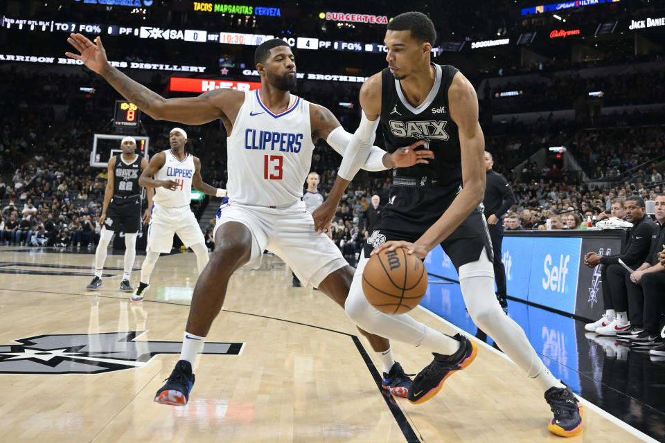 San Antonio Spurs' Victor Wembanyama, right, drives against Los Angeles Clippers' Paul George during the first half of an NBA basketball game Wednesday, Nov. 22, 2023, in San Antonio. (AP Photo/Darren Abate)