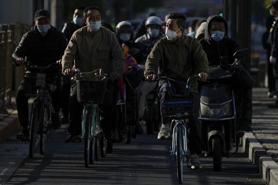 Cyclists and motorists wearing face masks ride on a street during the opening ceremony of the 20th National Congress of China's ruling Communist Party in Beijing, Sunday, Oct. 16, 2022. The overarching theme emerging from China's ongoing Communist Party congress is one of continuity, not change. The weeklong meeting is expected to reappoint Xi Jinping as leader, reaffirm a commitment to his policies for the next five years and possibly elevate his status even further as one of the most powerful leaders in China's modern history. (AP Photo/Andy Wong)