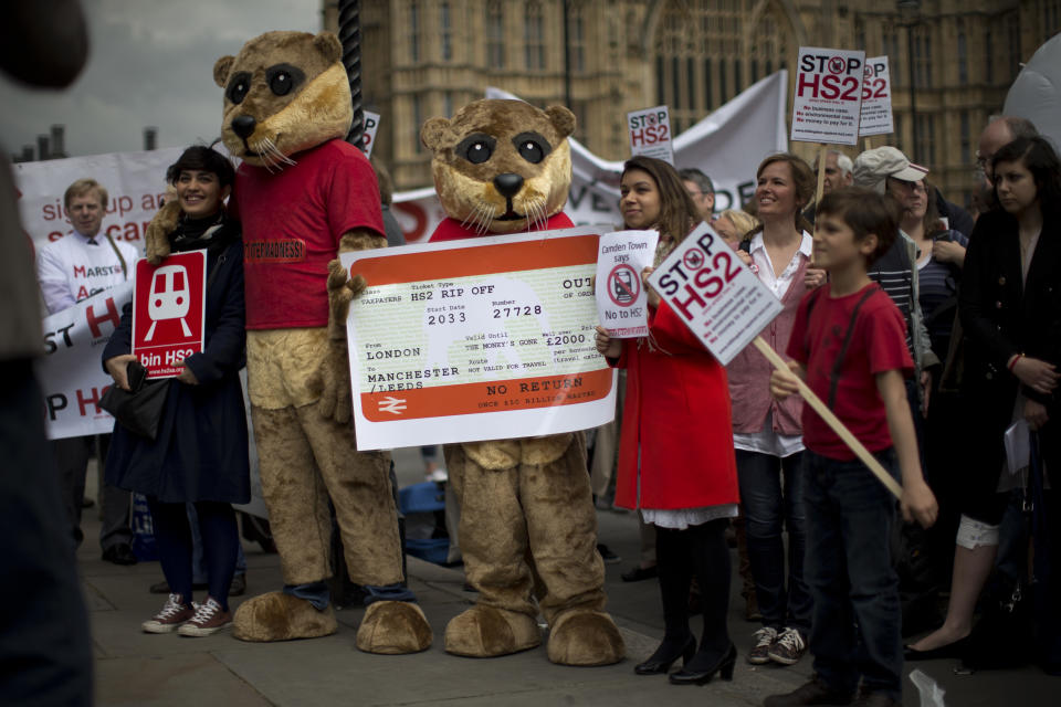 Campaigners against the construction of the proposed HS2 (High Speed 2) railway line, including two dressed up as otters, pose for photographs for the media with banners and an inflatable white elephant as they protest outside the Houses of Parliament in London, Monday, April 28, 2014.  The protest was held Monday to coincide with a debate in Parliament on HS2.  A white elephant is a term given to a scheme or object considered by some people to offer little value.  (AP Photo/Matt Dunham)