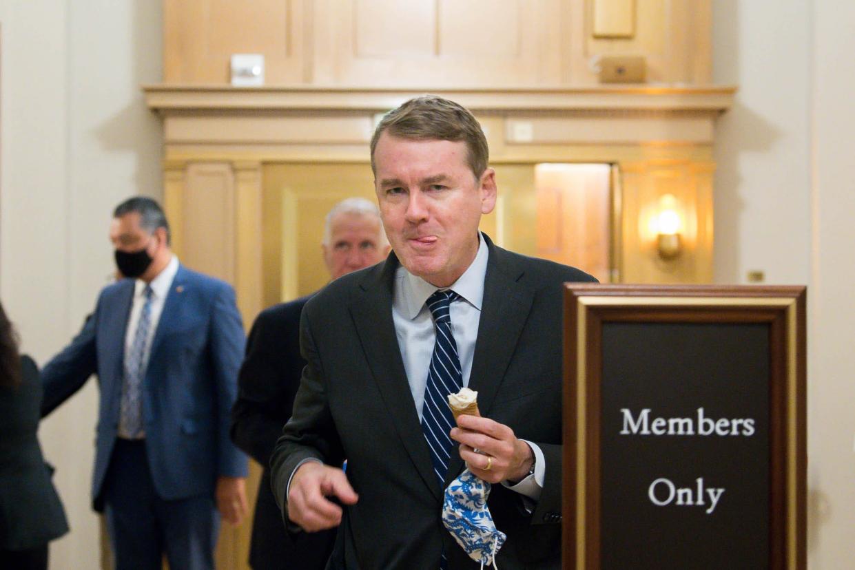Democratic Sen. Michael Bennet of Colorado eats an ice cream cone while walking in the halls of the US Capitol during the budget resolution proceedings on August 10, 2021 in Washington, DC.