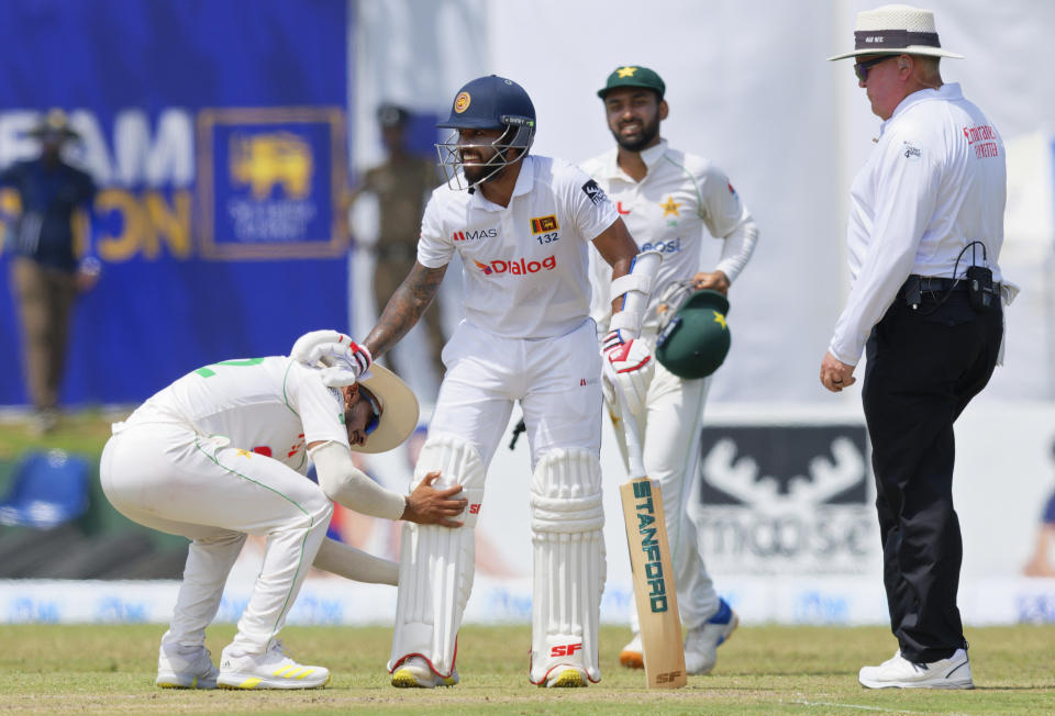 A cricketer adjusts the batting pads of Sri Lanka's Kusal Mendis during the first day of the first test cricket match between Sri Lanka and Pakistan in Galle, Sri Lanka, Saturday, July 16, 2022. (AP Photo)