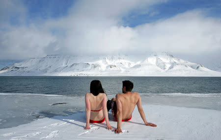 FILE PHOTO: Climate activists Lesley Butler and Rob Bell (R) "sunbathe" on the edge of a frozen fjord in the Norwegian Arctic town of Longyearbyen April 25, 2007. REUTERS/Francois Lenoir/File Photo