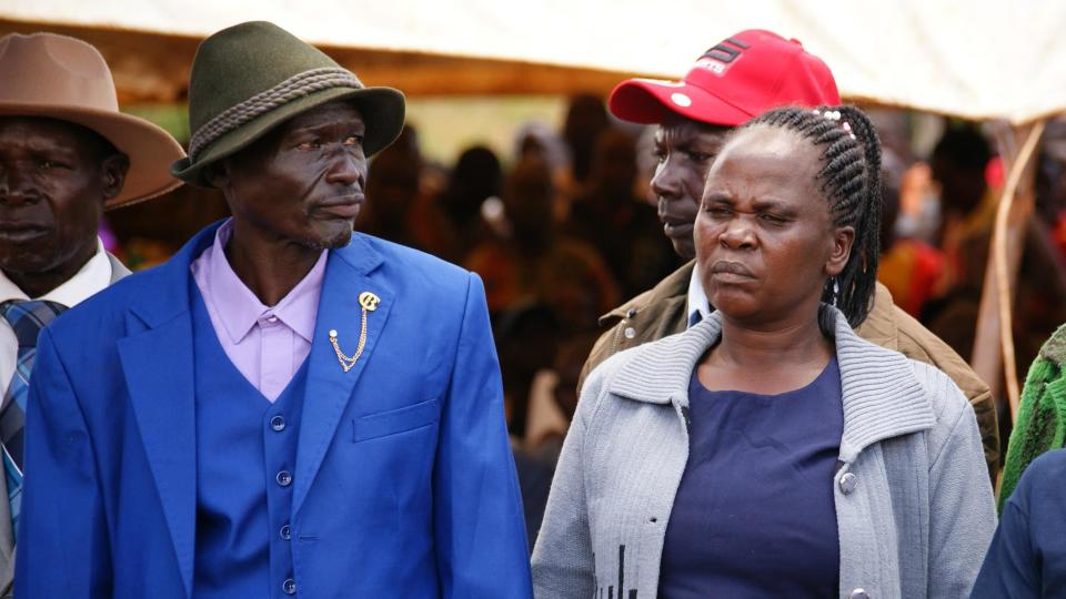 Two smartly dressed adults - a man and a woman - at the funeral 