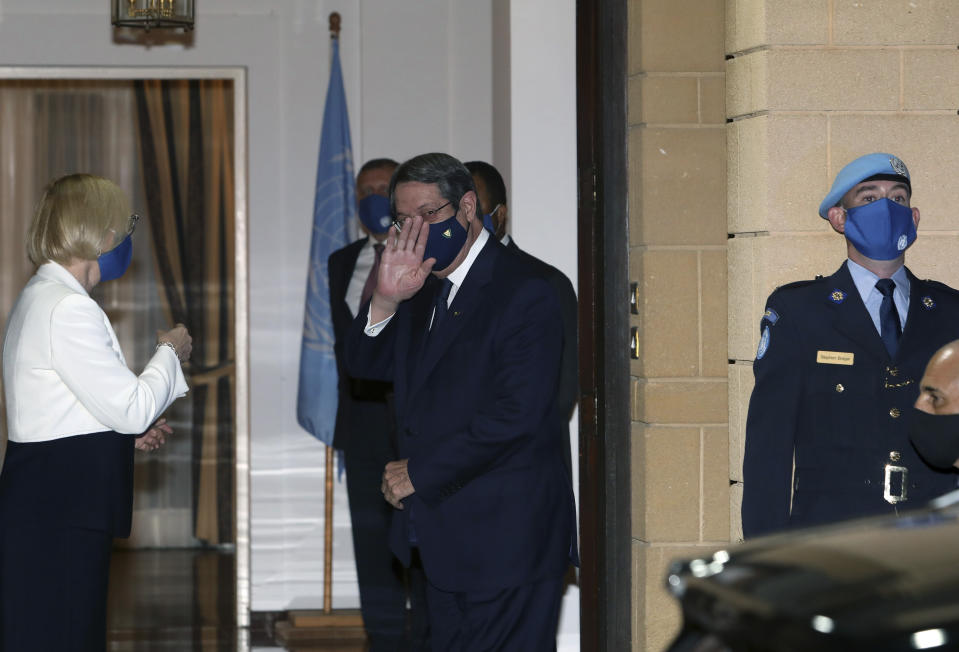 Nicos Anastasiades, the Greek Cypriot President of war-divided Cyprus, waves to the media next from Elizabeth Spehar, left, the head of the United Nations Peace Keeping Force in Cyprus, arrives the Spehar's official residence before their talks with Turkish Cypriot leader inside the U.N.-controlled buffer zone separating the breakaway Turkish Cypriot north from the internationally recognized Greek Cypriot south in the capital Nicosia, Cyprus, on Tuesday, Nov. 3, 2020. Anastasiades and Tatar held their first informal face-to-face meeting hosted by Spehar following Tatar's election as Turkish Cypriot leader last month amid hopes of a possible resumption of dormant reunification talks. (Katia Christodoulou Pool via AP)