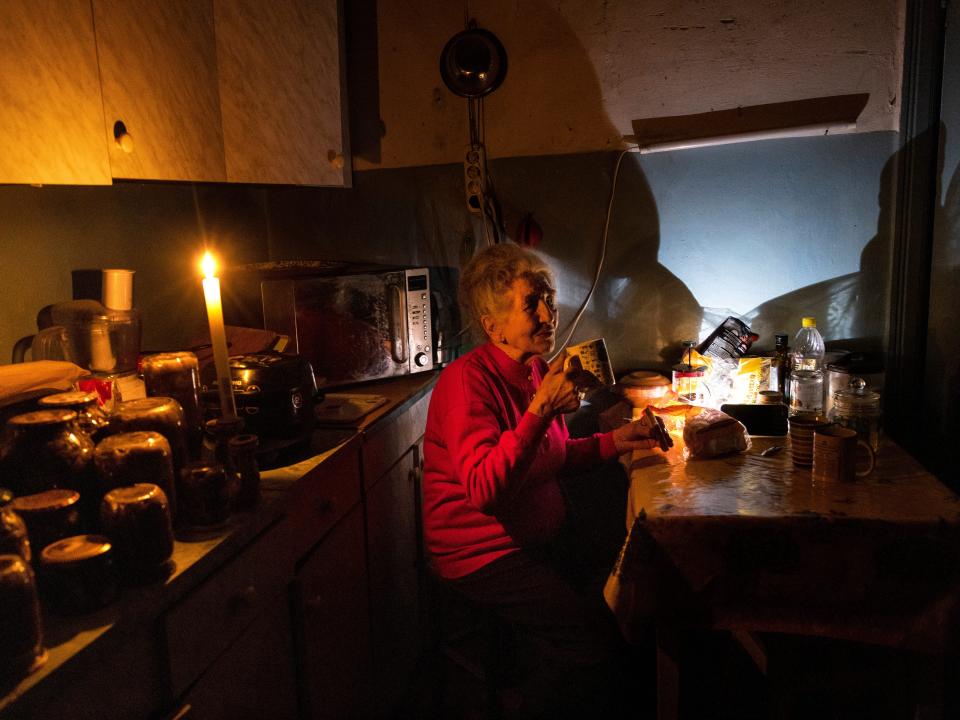 A woman sits in her kitchen surrounded by candles.