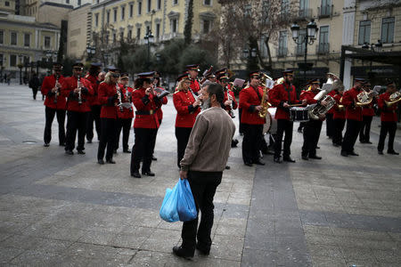 A man holds bags with goods as the Big Band of the Municipality of Athens performs in central Athens, Greece, February 21. 2017. REUTERS/Alkis Konstantinidis