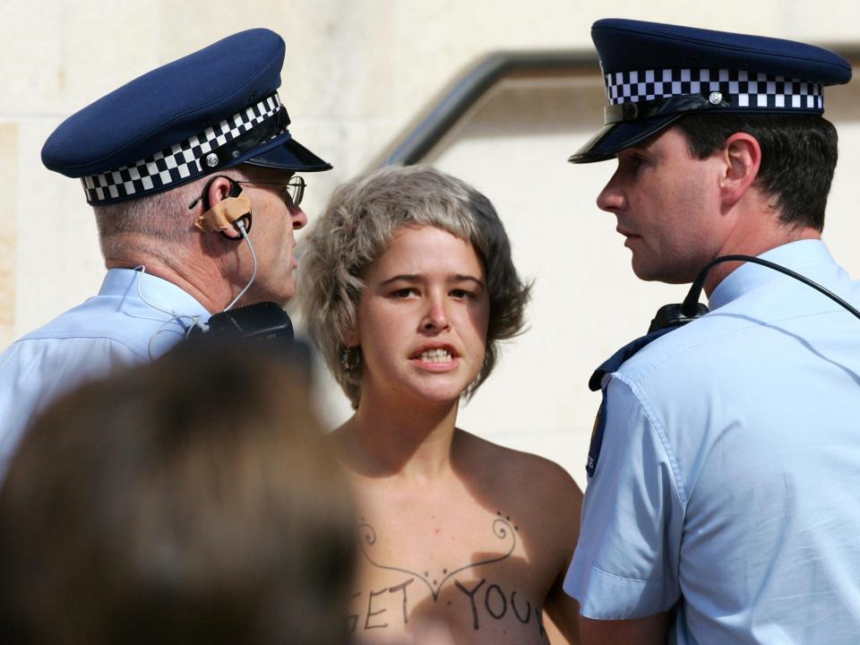 A woman protesting Prince Charles is led away by police in Wellington, New Zealand.