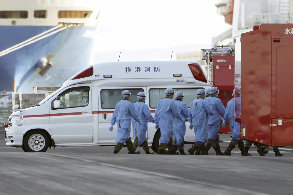 Members of Japan Self Defense Forces walk into the quarantined cruise ship Diamond Princess in the Yokohama Port Sunday, Feb. 9, 2020, in Yokohama, Japan. China's death toll from the new virus outbreak has risen to over 800, surpassing the number of fatalities in the 2002-03 SARS epidemic, as other governments stepped up efforts to block the disease. (AP Photo/Eugene Hoshiko)