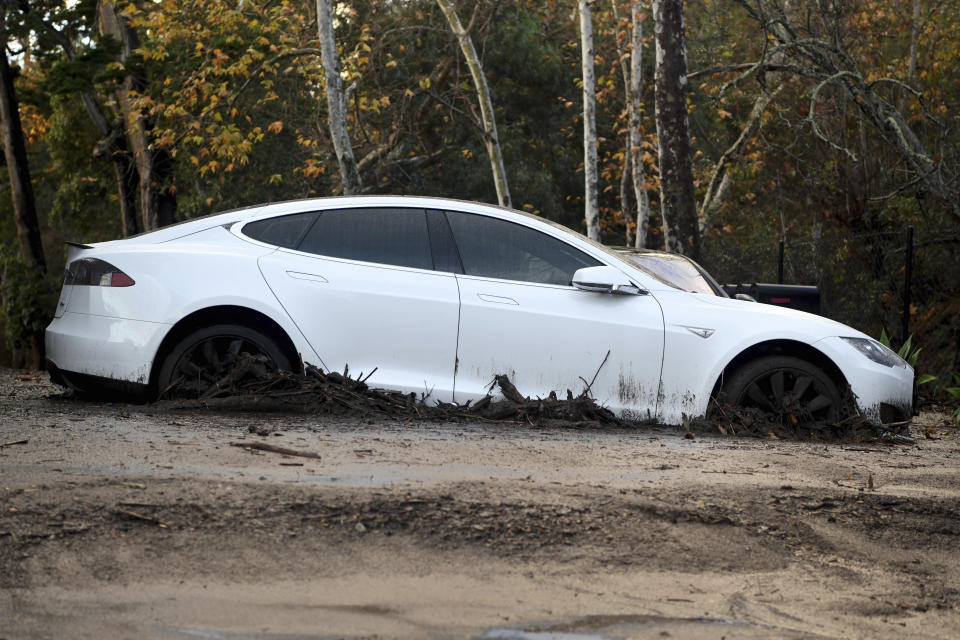 Tesla istuu mudassa asuinkompleksissa Montecitossa, Kaliforniassa, tiistaina 9. tammikuuta 2018. Kymmenet kodit lakaistiin pois tai vaurioituivat pahoin tiistaina, kun kaatosateet lähettivät mutaa ja lohkareita alas kukkuloista, joita jätti kasvillisuus riisuttiin jättimäisen metsäpalon vuoksi. raivosi Etelä-Kaliforniassa viime kuussa. (AP Photo/Michael Owen Baker)