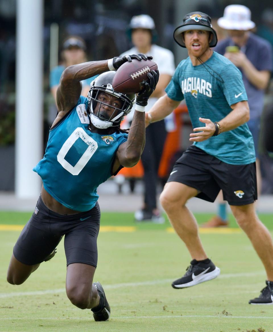 Jaguars' wide receiver Calvin Ridley (0) stretches to bring in a pass during training camp while receivers' coach Chad Hall looks on at the Miller Electric Center.