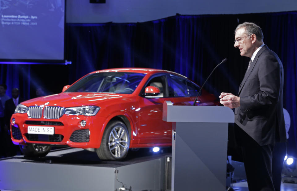 Dr. Norbert Reithofer, Chairman of the Board of Management, BMW Group, right, speaks with a new BMW X4 in the background during a news conference at the BMW manufacturing plant in Greer, S.C., Friday, March 28, 2014. The company announced a $1 billion expansion for the plant. (AP Photo/Chuck Burton)