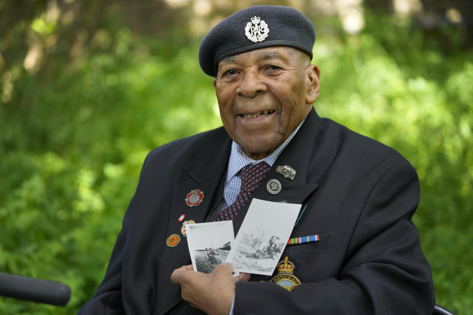 Gilbert Clarke a D-Day veteran holds up old photographs of himself as he is interviewed near his home in east London, Wednesday, May 15, 2024. Clarke, now 98, is one of more than 3 million men and women from South Asia, Africa and the Caribbean who served in the British military during World War II. (AP Photo/Kirsty Wigglesworth)