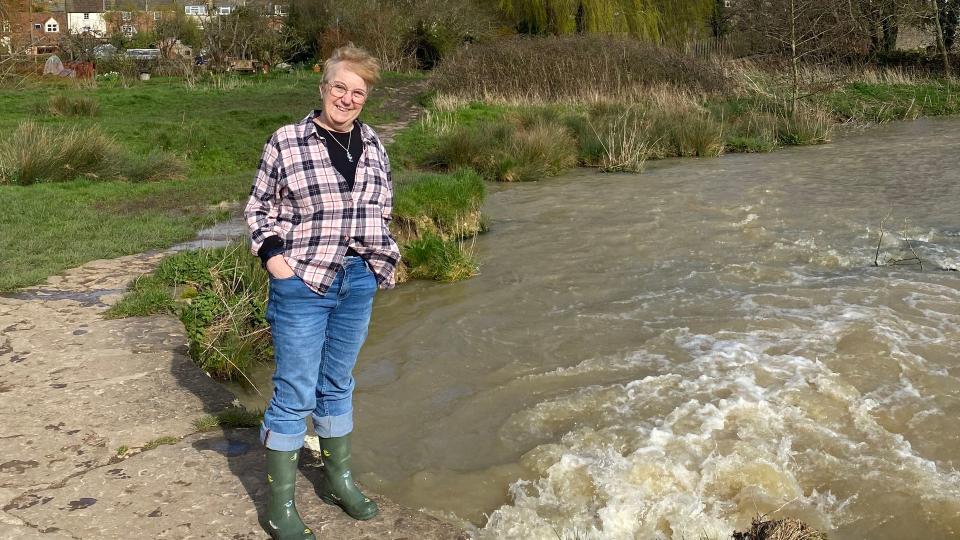 Woman standing by a river in wellies 