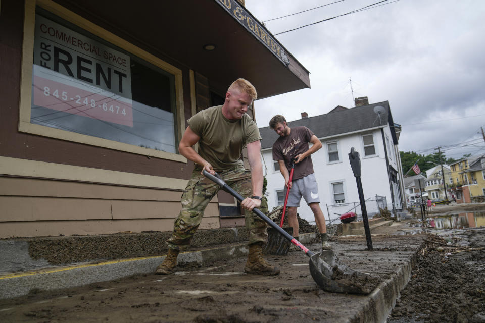 Volunteers help clear Main Street of debris after floodwaters subsided, Monday, July 10, 2023, in Highland Falls, N.Y. Heavy rain has washed out roads and forced evacuations in the Northeast as more downpours were forecast throughout the day. One person in New York's Hudson Valley has drowned as she was trying to leave her home. (AP Photo/John Minchillo)