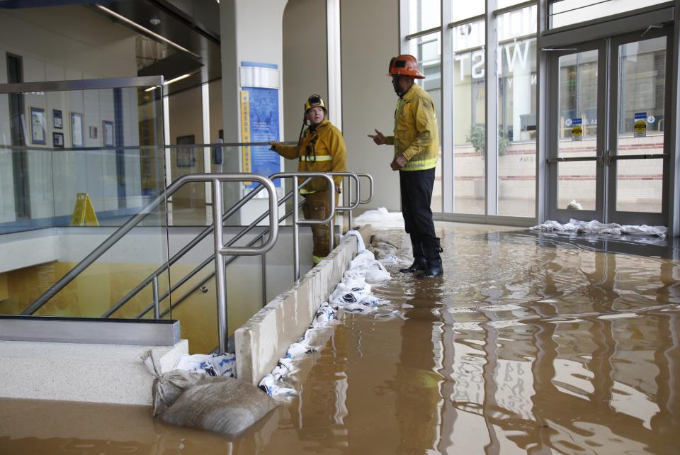 Firefighters talk after damming up a stairway inside UCLA's Pauley Pavilion sporting arena as water flows from a broken thirty inch water main that was gushing water onto Sunset Boulevard near the UCLA campus in the Westwood section of Los Angeles July 29, 2014. The geyser from the 100-year old water main flooded parts of the campus and stranded motorists on surrounding streets. REUTERS/Danny Moloshok