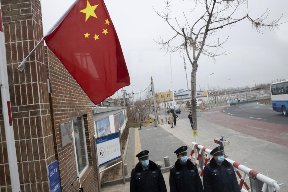 Guardias de seguridad con máscaras faciales a causa del coronavirus vigilan la entrada de la planta eléctrica Huadian Beiran Corporation en Beijing, el jueves 27 de febrero de 2020. (AP Foto/Ng Han Guan)