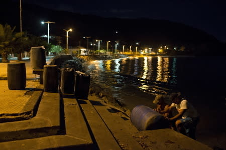 Men carry containers filled with gasoline in the bay of Rio Caribe, a town near caribbean islands, in the eastern state of Sucre, Venezuela October 30, 2015. REUTERS/Carlos Garcia Rawlins