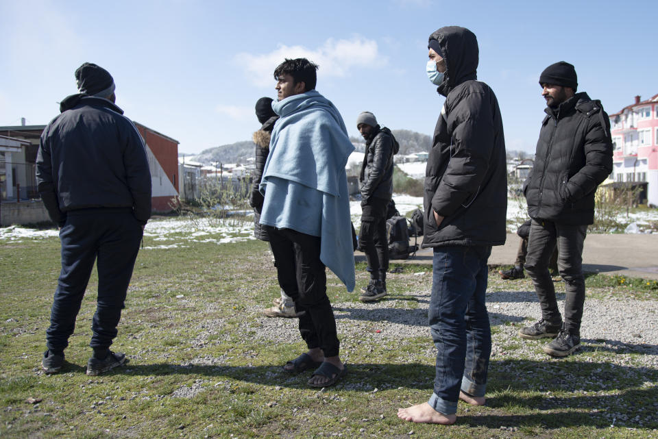 Migrants stand outside the Miral camp, in Velika Kladusa, Bosnia, Wednesday, April 7, 2021. Bosnia is seeing a rise in coronavirus infections among migrants and refugees living in its camps, as it struggles to cope with one of the Balkans' highest COVID-19 death and infection rates among the general population.(AP Photo/Davor Midzic)