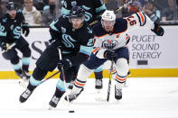 Edmonton Oilers center Connor McDavid (97) pursues Seattle Kraken center Alex Wennberg (21) during the first period of an NHL hockey game Friday, Dec. 3, 2021, in Seattle. (AP Photo/Elaine Thompson)