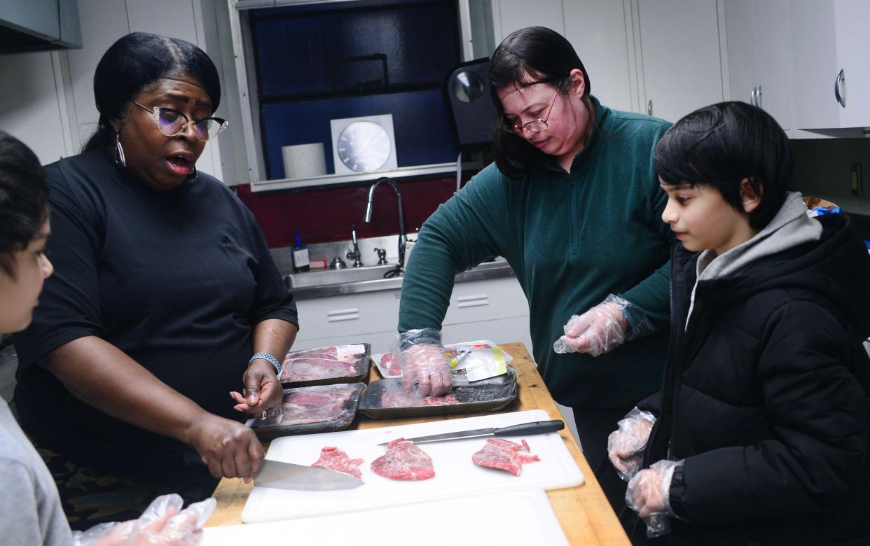 Brenda Johnson demonstrates how to properly hold and use a chef's knife to Austin Pulivarthy, 10, right, during a Youth and Parent Cooking Classes on Friday, Feb. 9, 2024, at the Family Matters Resource Center.