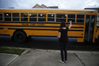 Rachel Adamus waves goodbye to her two children, Paul and Neva, as they ride the bus for the first day of school on Monday, Aug. 3, 2020, in Dallas, Ga. (AP Photo/Brynn Anderson)