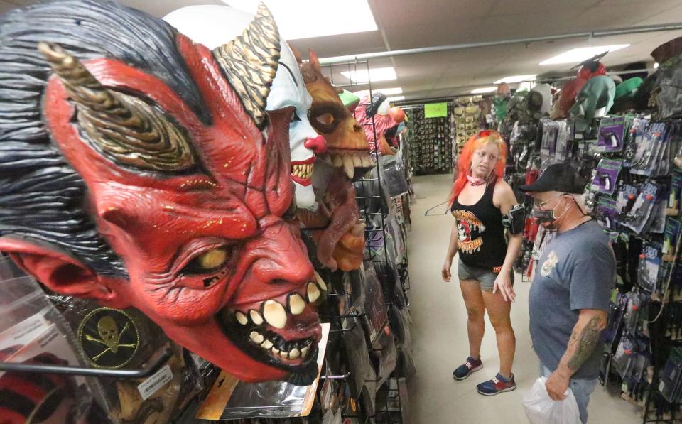 A customer makes a selection with help from store manager Pyro (at left) ahead of Halloween 2022 at the Halloween Megastore in Daytona Beach. This year, the store opened for customers a week ahead of Labor Day, earlier than last year.  "We've had a lot of people coming in already," Pyro said.